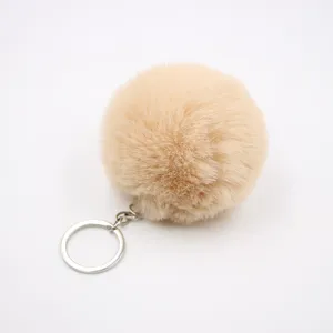 Fluffy plush pom pom keychain detail shot, soft faux rabbit fur charm for bags and cars.