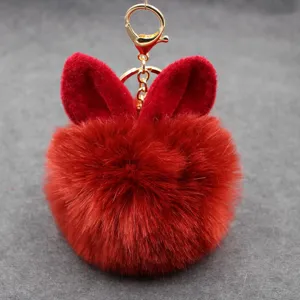 Detailed close-up of a cute red faux fur bunny ear keychain, fluffy pom pom pendant charm.