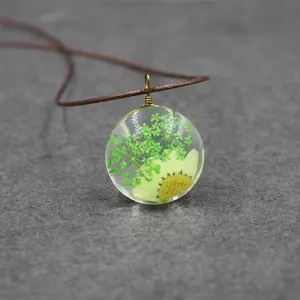 Close-up detail of green pressed flower resin pendant necklace, botanical forest style jewelry.