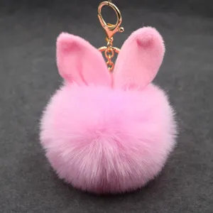 Detailed close-up view of fluffy pink rabbit ears plush pom pom keychain and metal clasp.