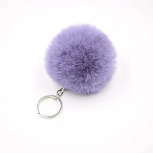 Close-up detail of the soft purple faux fur pom-pom keychain and metal ring hardware.