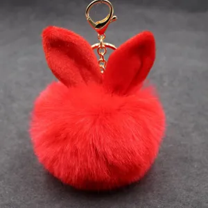Red fluffy bunny ear plush pom pom keychain detail close up shot, soft faux fur bag charm.