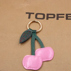 Leuke kersen leer tas bedel en autosleutelhanger, stijlvol modeaccessoire voor vrouwen.