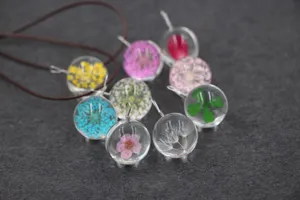 Handcrafted dried flower glass ball pendant necklace detail showing colorful preserved botanical specimens.