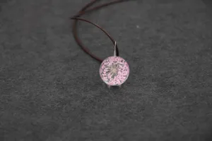Handmade dried flower glass ball pendant necklace detail view with pink lace flowers.