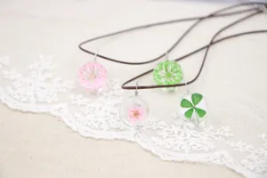 Handmade dried flower glass ball pendant necklace detail, featuring clear botanical specimens inside.