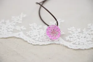 Handmade dried flower glass ball pendant necklace detail showing pink floral charm.