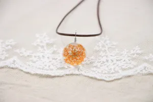 Close-up detail view of the handmade dried orange flower glass ball pendant necklace.