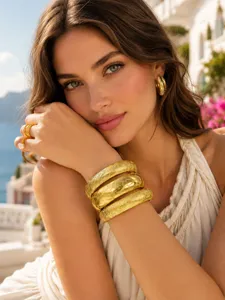 Close-up detail of wide gold-plated stainless steel cuff bracelet with matte engraved floral pattern.