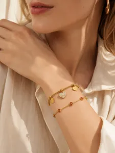 Elegante pulsera doble de acero inoxidable chapado en oro 18k con dijes de corazón de circonita.