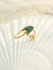 Nahaufnahme des ozeaninspirierten offenen Rings mit blauen Zirkonia und Herz auf Muschel.