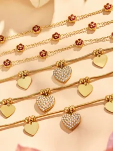 Vista detallada de pulsera de acero inoxidable chapado en oro con dijes de corazones y rosas.