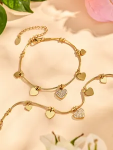 Pulsera de acero inoxidable chapada en oro con dijes de corazón y circonitas.