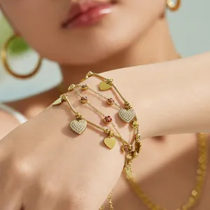 Pulsera de acero dorado con multiples hilos y corazon zircon en la muneca vista principal
