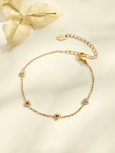 Detailed close-up of a gold-plated heart zircon bracelet with sparkling red and pink stones.
