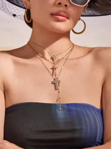 Layered gold-tone cross pendant necklace with sparkling cubic zirconia and chic bead chains.