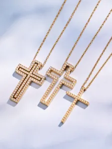 Close-up of gold pave zircon cross pendant necklaces showing delicate hollow detail and chain.