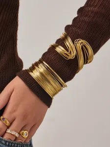 Gros plan détaillé de bracelets joncs dorés en fil spiralé multicouche portés au bras.