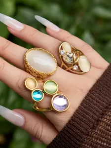 Primo piano dettagliato di anelli alla moda placcati in oro con occhi di gatto e pietre.