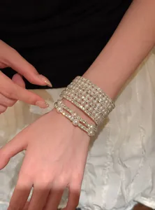 Gros plan de bracelets empilés en perles et strass multicouches, bijou rétro élégant.