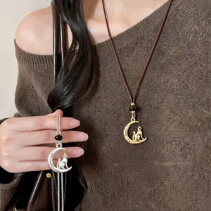 Close-up detail shot of the crescent moon and cat pendant necklace worn on knitted sweater.