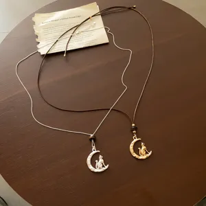 Detail shot of cat and moon pendant necklace with brown leather cord and tiger eye bead.