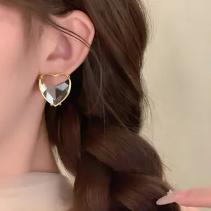 Nahaufnahme von herzförmigen Kristall-Ohrringen mit goldenem Rand, elegante Detailansicht.