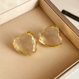 Exquisite klare Kristall-Herz-Ohrringe mit Goldrand, eleganter Schmuck-Detailaufnahme.