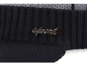Gros plan détaillé du bonnet d'hiver en tricot chaud avec visière et badge en métal.