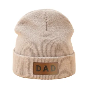 Beige gebreide muts voor heren en dames met stijlvolle DAD leren patch voor winterse warmte.