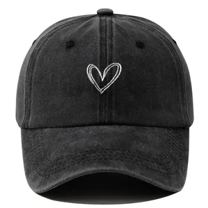 Détail en gros plan de la casquette de baseball noire délavée avec broderie cœur blanc.