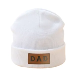 Gedetailleerd weergave van witte gebreide muts met bruine DAD leren patch, warme muts.