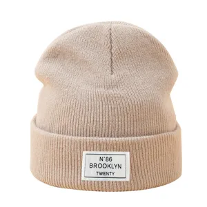 Bonnet en tricot beige d'hiver, bonnet chaud et confortable avec etiquette de lettre retro stylée.