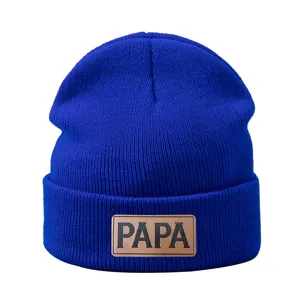 Gorro de punto azul de invierno detalle con parche de cuero marrón cálido y elegante.