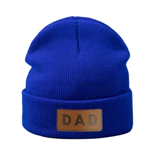 Gedetailleerd aanzicht van blauwe gebreide muts met bruine DAD lederen patch warme muts