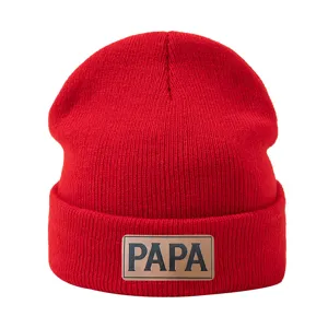 Vista detallada del gorro de punto rojo con un elegante parche de cuero y textura suave.