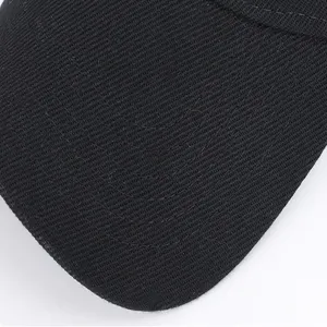 Black baseball cap brim detail close-up showing fine twill fabric weave and neat stitching texture.