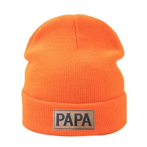 Detalle del gorro de punto naranja con elegante parche de cuero y textura detallada.