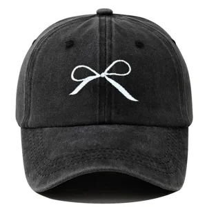 Casquette de baseball en coton lavé noir avec broderie nœud blanc, style streetwear décontracté.