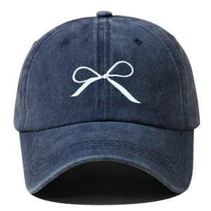 Gros plan sur la délicate broderie de nœud blanc sur la casquette en denim vieilli.