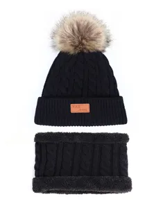 Detailansicht des schwarzen Strickmützen und Schal Sets mit weichem Fellpompon und warmem Stoff.