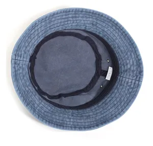 Close up view of the inner lining and washing label of a blue washed cotton bucket hat.