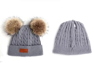 Children grey knitted beanie hat with double faux fur pom poms and leather patch detail.
