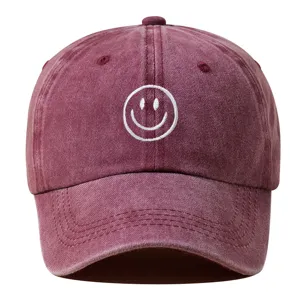Gros plan détaillé de la casquette de baseball en coton lavé avec visage souriant brodé blanc.