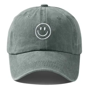 Gros plan sur la casquette de baseball en coton lavé gris, détail visage souriant brodé.