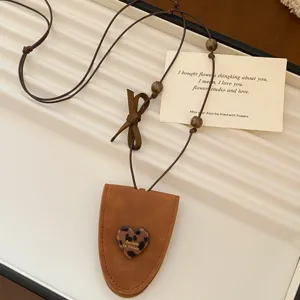 Nahaufnahme der braunen Leder Brillenclip Halskette mit Leoparden Herz Anhänger Schleife.
