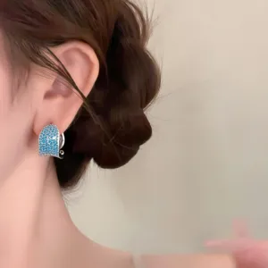 Primer plano de pendientes de tuerca circonita azul estilo corte vintage, tono plateado elegante.