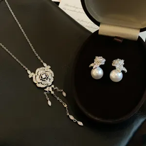 Vue détaillée de collier à pampilles de fleurs en zircon et boucles d'oreilles perles.