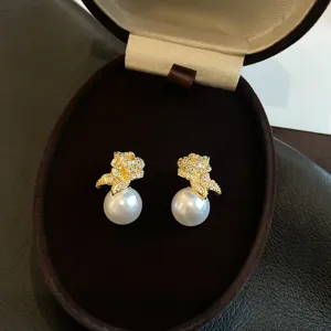 Gros plan détaillé de magnifiques boucles d'oreilles perles fleurs strass dans un écrin.