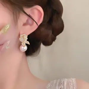Boucles d'oreilles perle fleur strass délicates plan détail, accessoire de mode élégant.